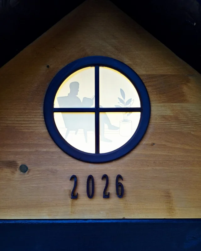 Das runde Giebelfenster mit Lesesilhouette und der Jahreszahl 2026.