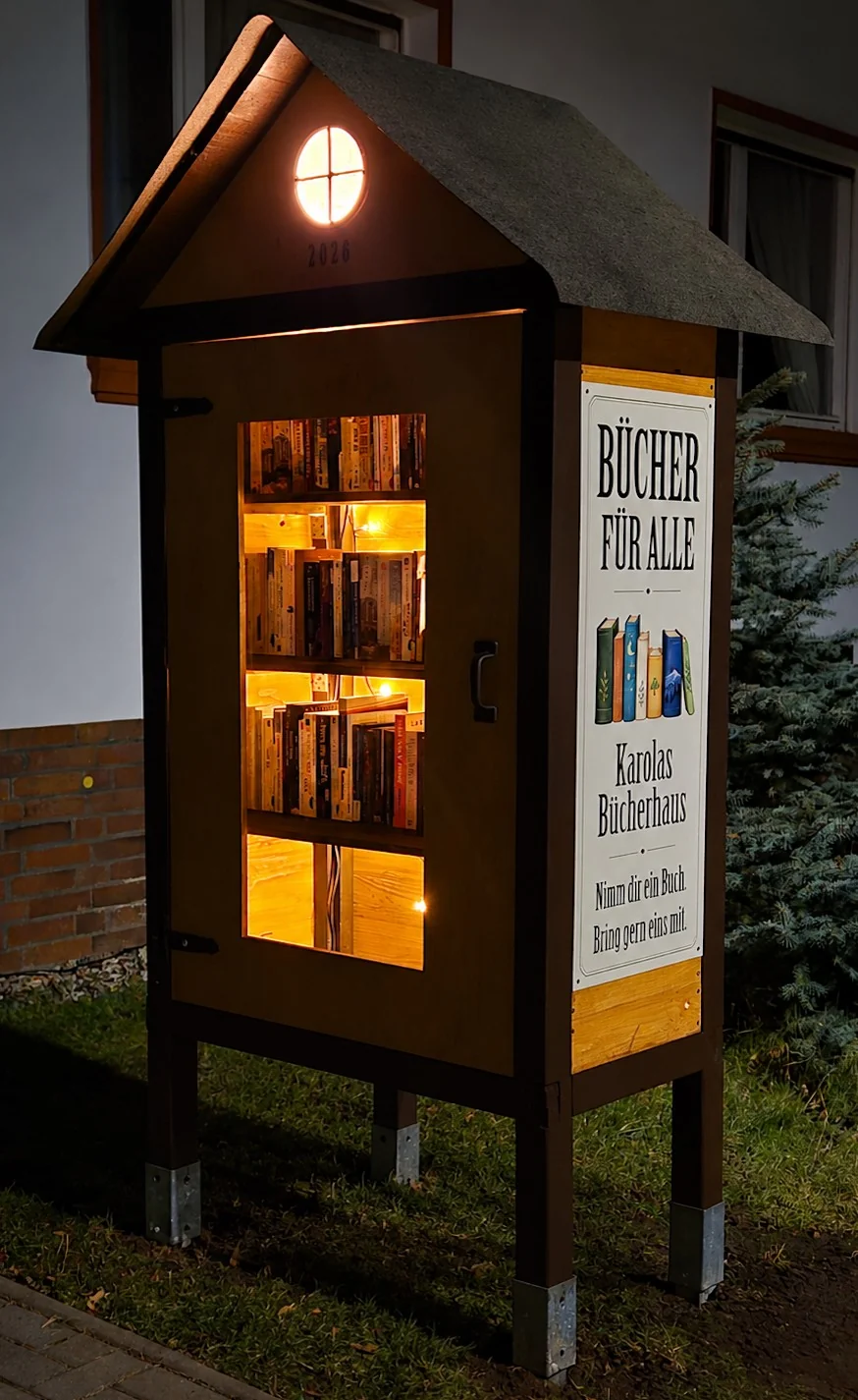 Karolas Bücherhaus bei Nacht. Warmes Licht beleuchtet die Bücherregale und das runde Giebelfenster.
